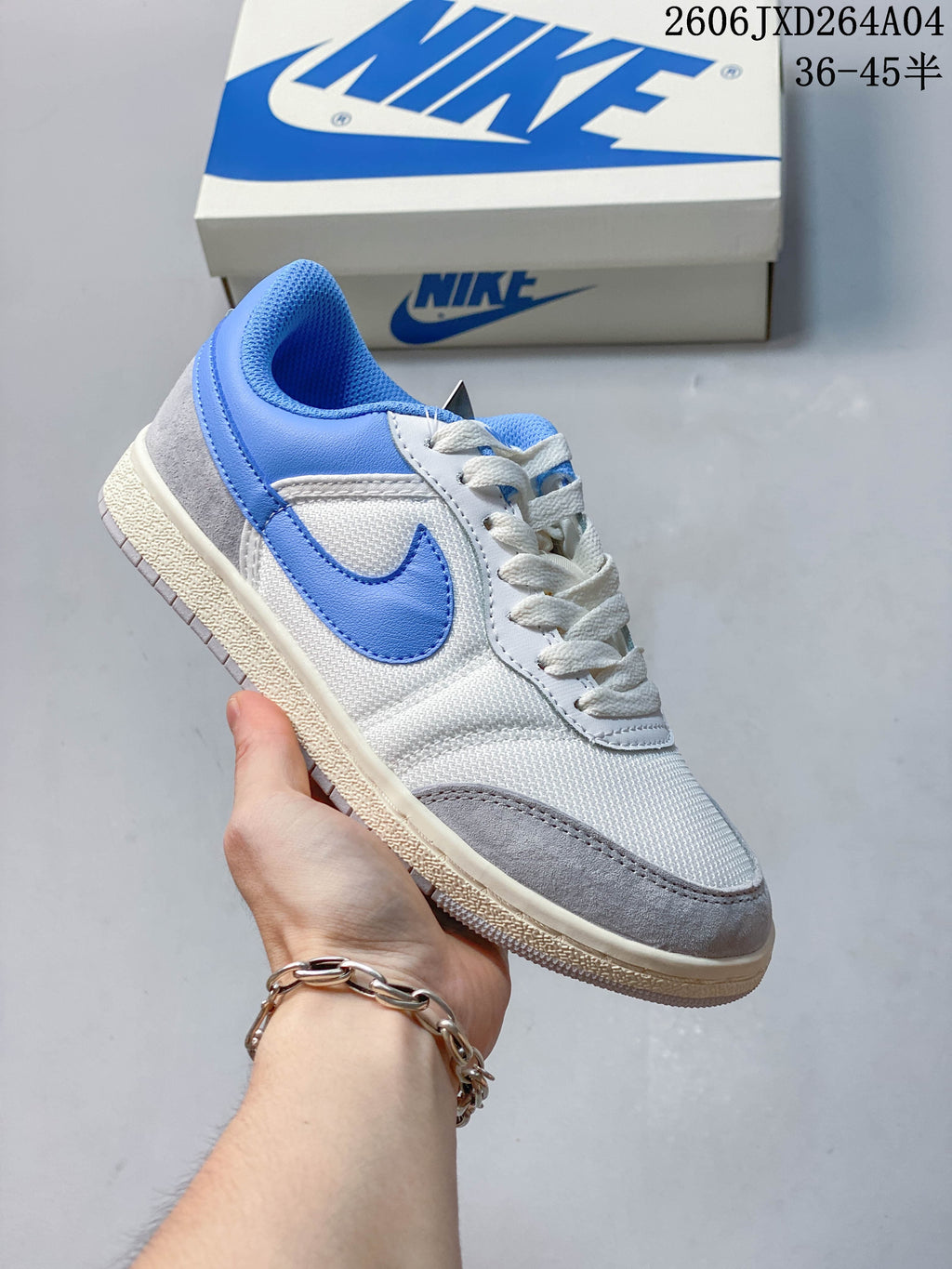 White low-top sneaker with blue accents, textured panels, and a light-colored sole