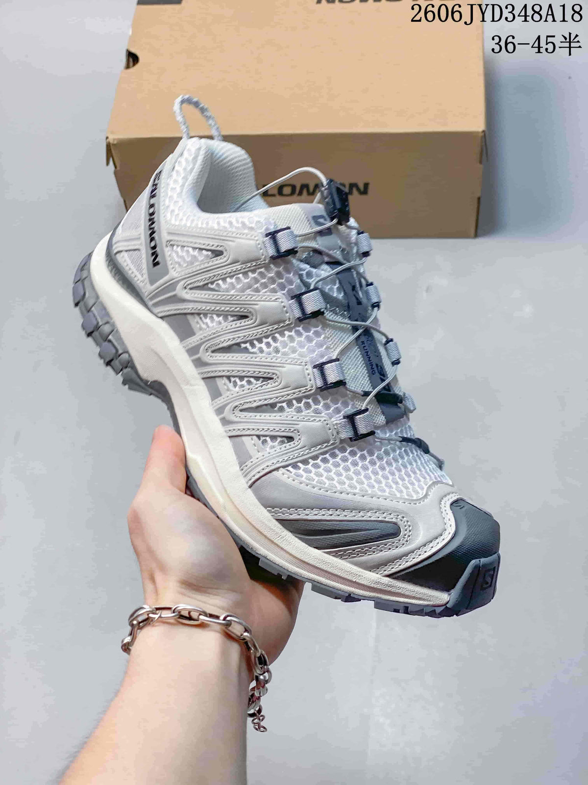 Angled side view of the white and gray Salomon trail running shoe.