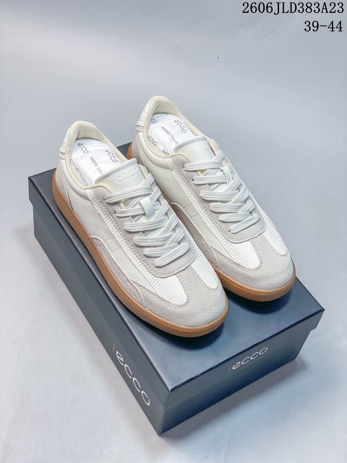 Pair of white and light gray ECCO lace-up sneakers with gum-colored soles, shown on a branded box