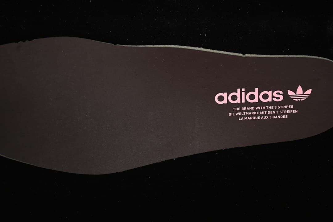 Dark shoe insert with adidas branding and pink trefoil logo.