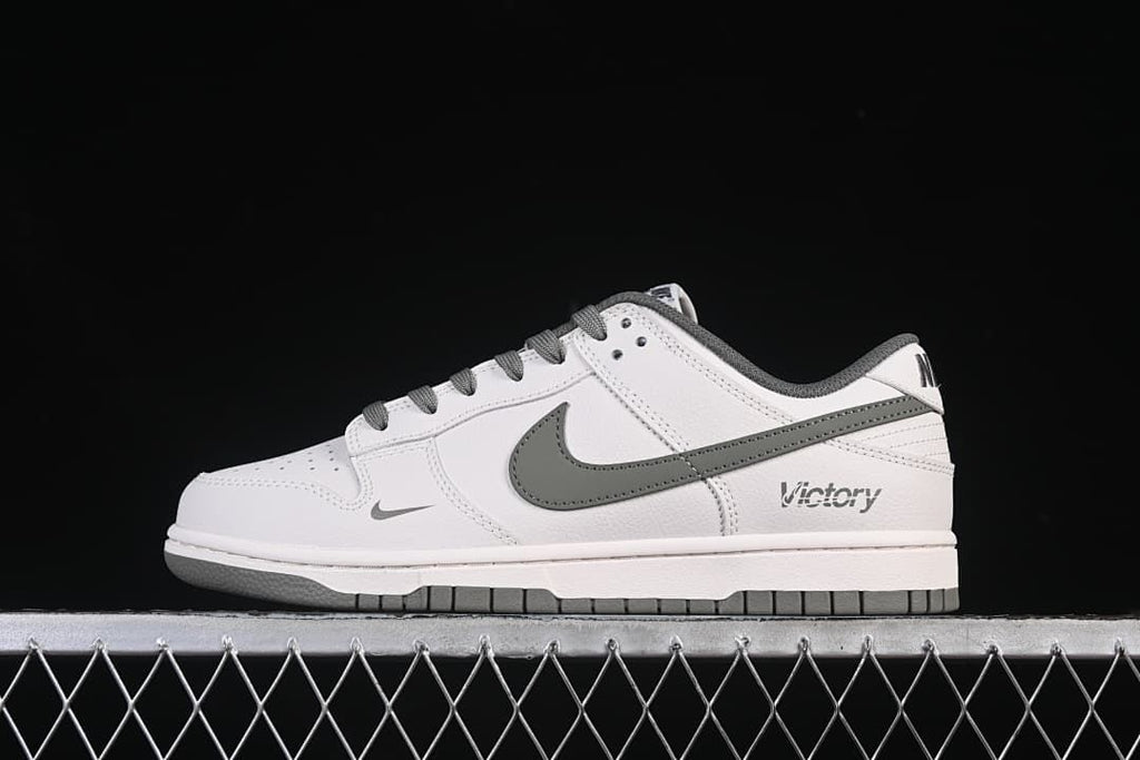 Side view of a white Nike SB Dunk Low with grey Swoosh, laces, and outsole details.
