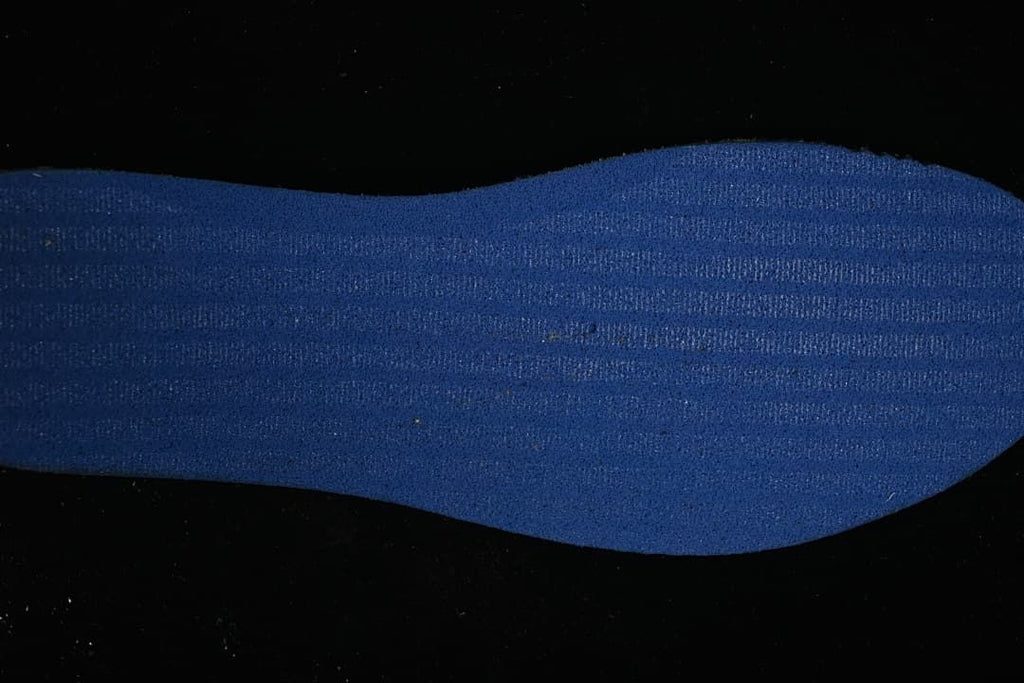 Blue shoe insert photographed against a dark background