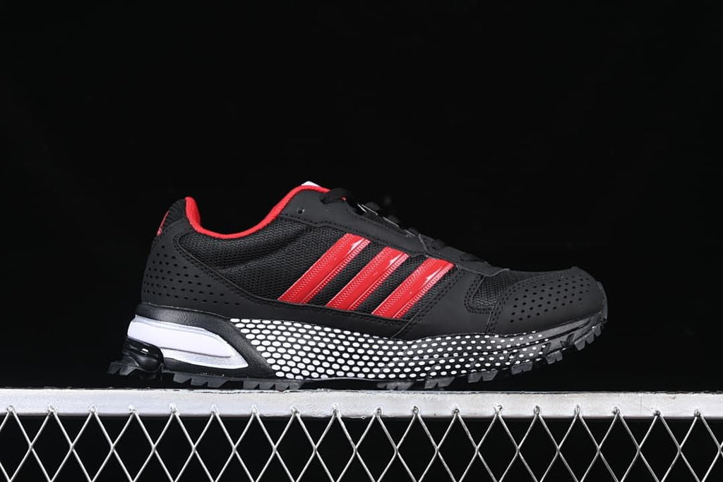 Side profile of the black sneaker with red stripes and dotted midsole.