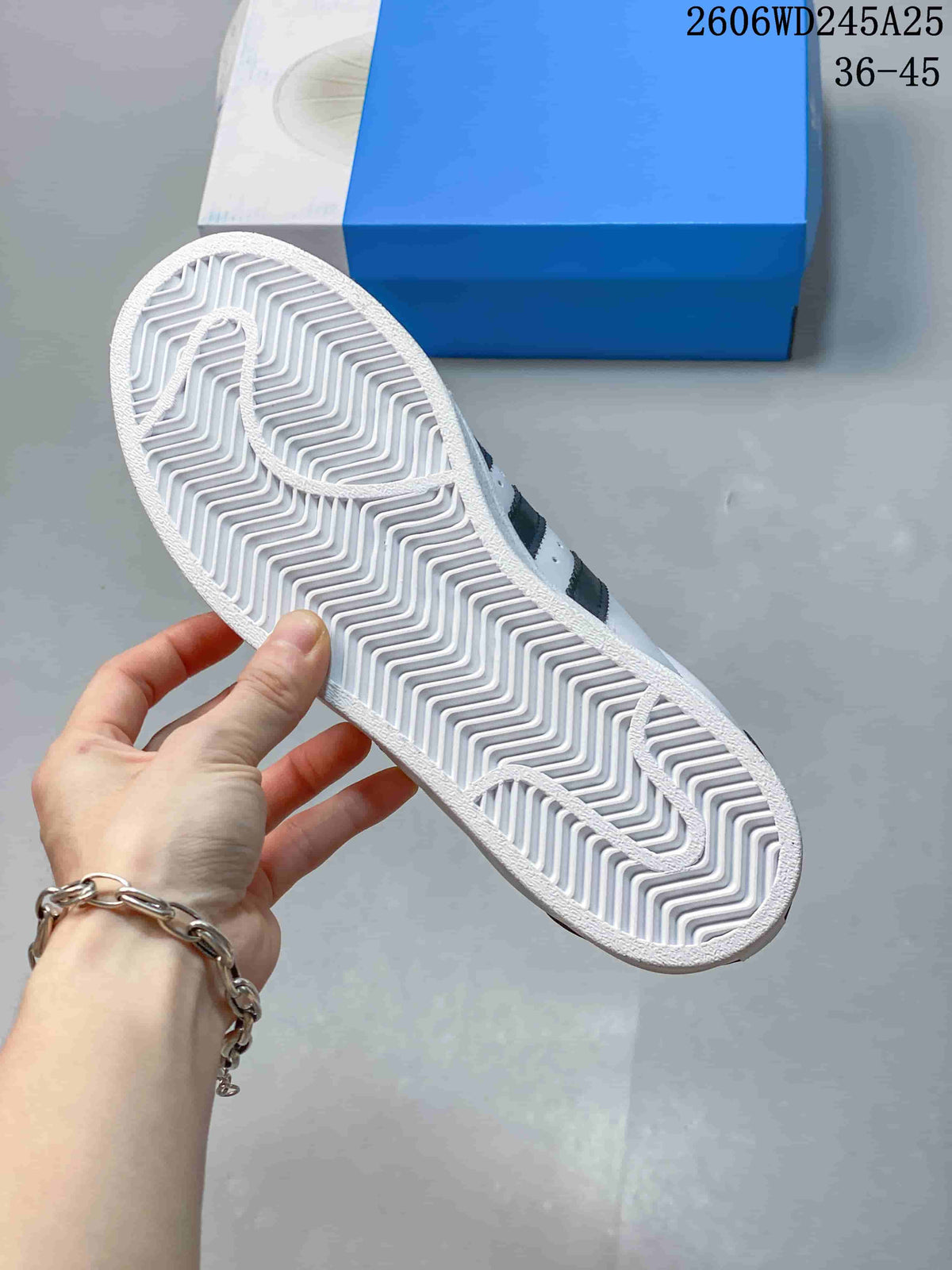 Underside of a white sneaker showing a patterned rubber outsole