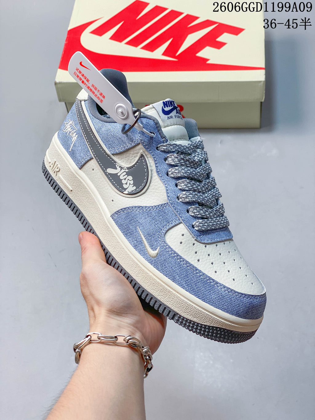 Angled side view showing the gray Swoosh with Stüssy lettering and a decorative charm.