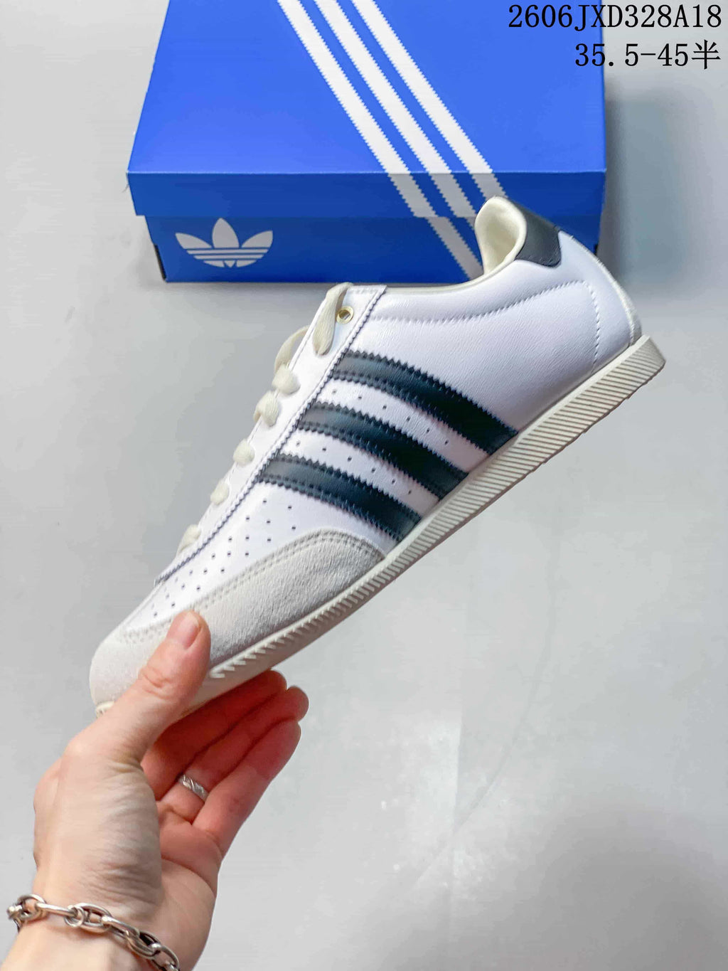 Side view of the white adidas Originals Japan sneaker with dark stripes and perforated panels