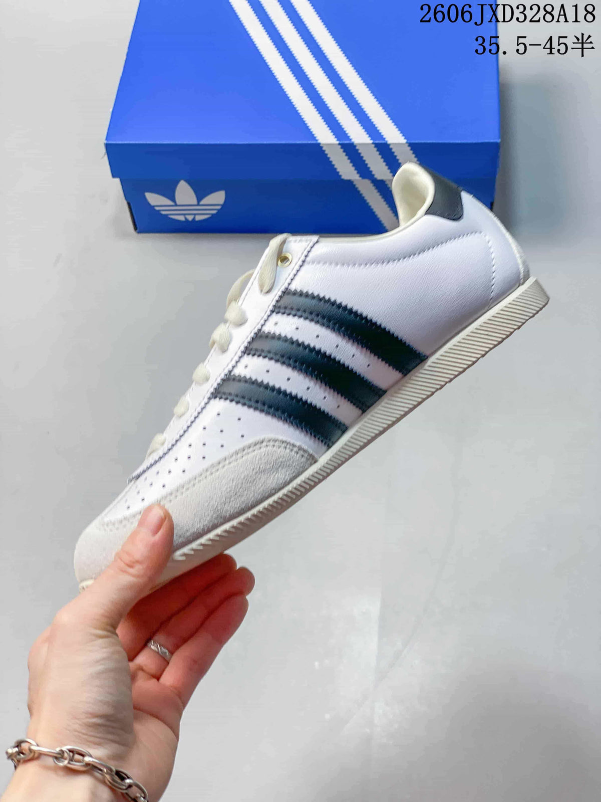 Side view of the white adidas Originals Japan sneaker with dark stripes and perforated panels