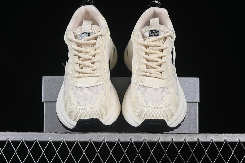 Front view of the pair of beige sneakers on the box