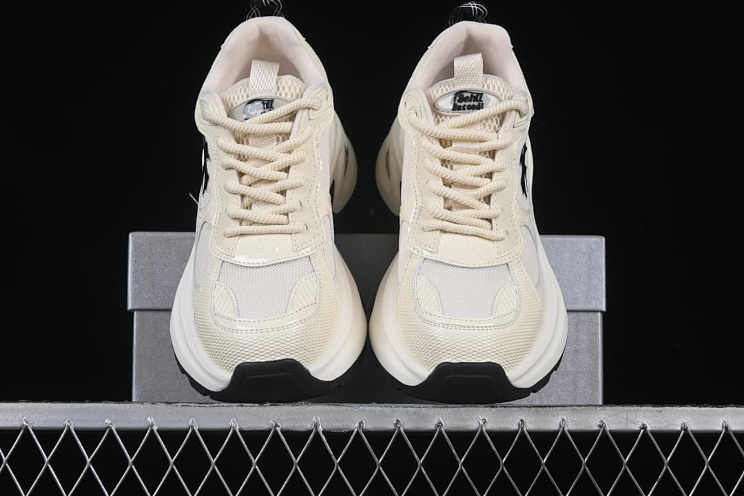 Front view of the pair of beige sneakers on the box