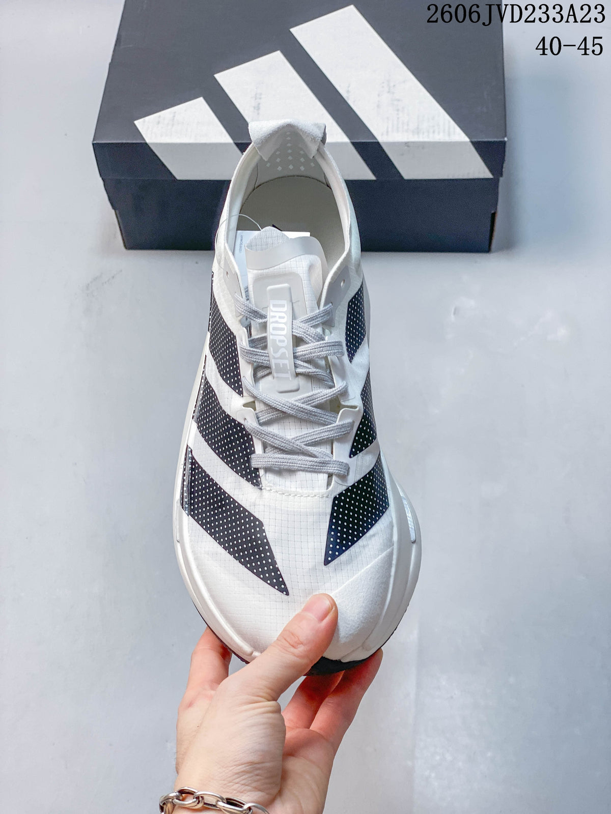 Front view of a white adidas running shoe with gray laces and dark patterned stripes