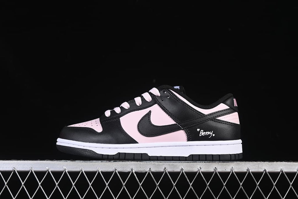 Side view of a black and pale pink low-top sneaker with a Swoosh and small Berry heel graphic.