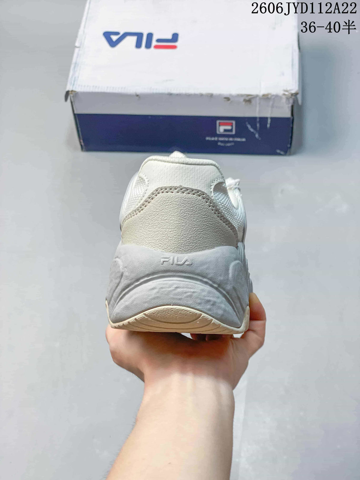 Rear view of a white and grey FILA sneaker with a sculpted sole