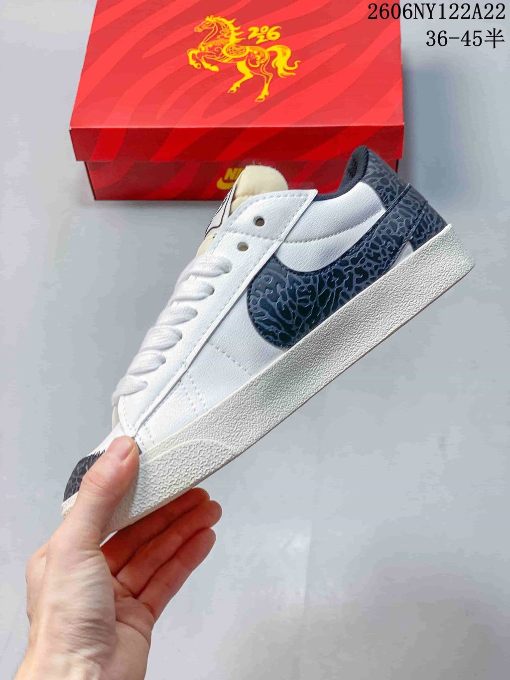 Side view of the low-top sneaker with a dark gray patterned Swoosh and heel accents.