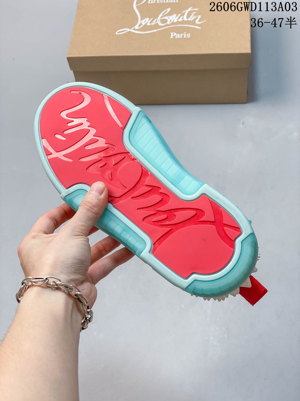 Bottom view of the sneaker showing a red outsole center and turquoise-colored sections