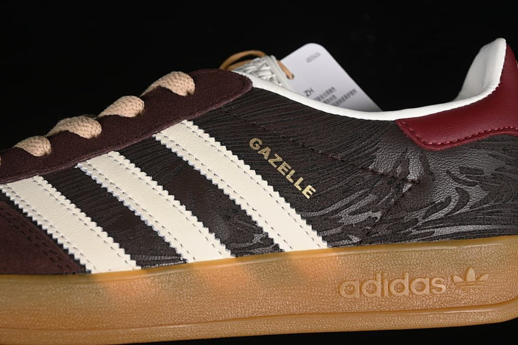 Close-up of the sneaker side showing off-white stripes, Gazelle lettering, and gum-colored sole.