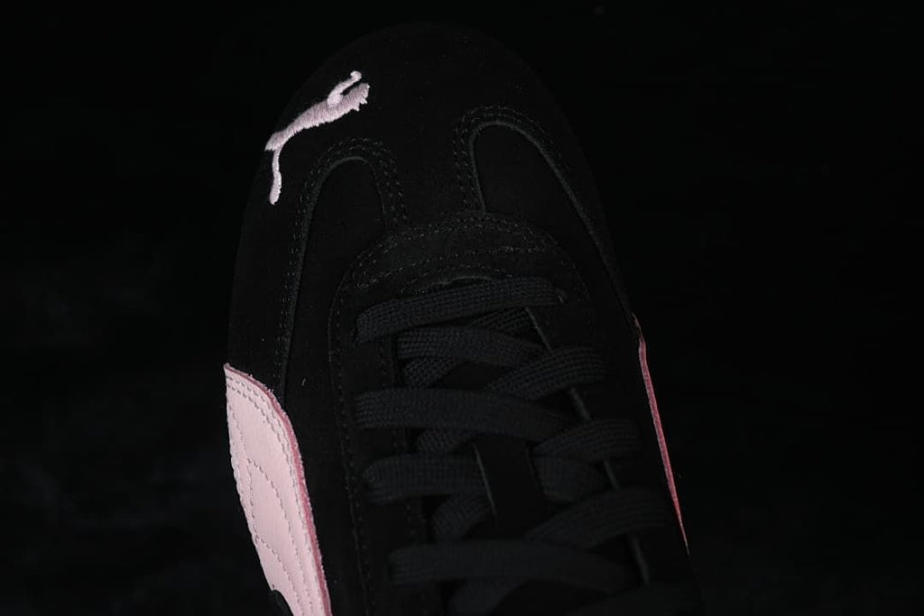 Top-front close-up of the black laces and embroidered Puma cat on the toe.