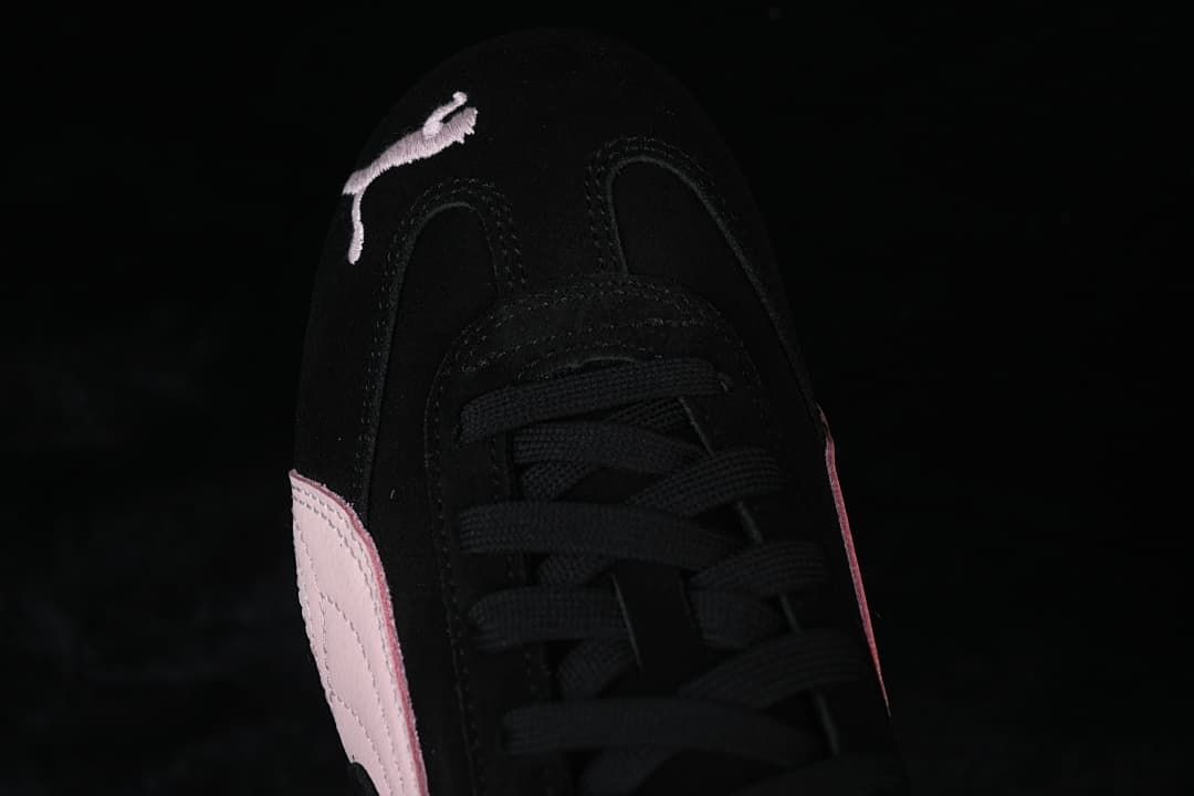 Top-front close-up of the black laces and embroidered Puma cat on the toe.