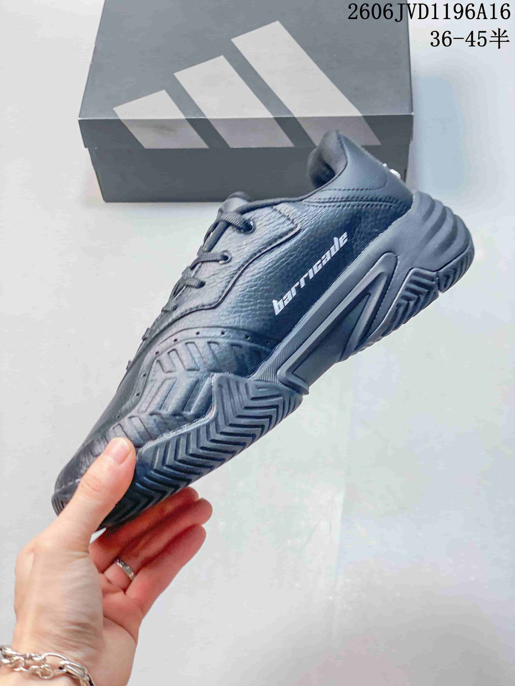 Side view of a dark grey tennis shoe with patterned outsole