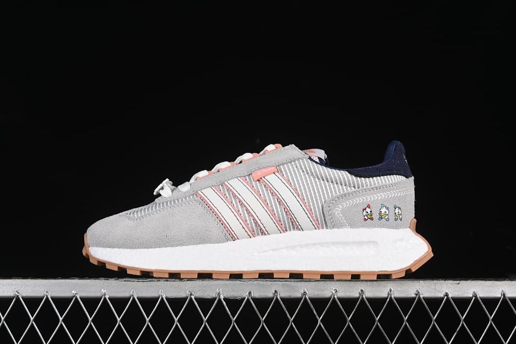 Side view of gray adidas Retropy E5 sneakers with pink stripes, navy heel accents, and character graphics