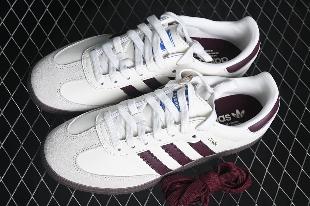 Pair of white and burgundy Samba OG EMMI sneakers with extra burgundy laces