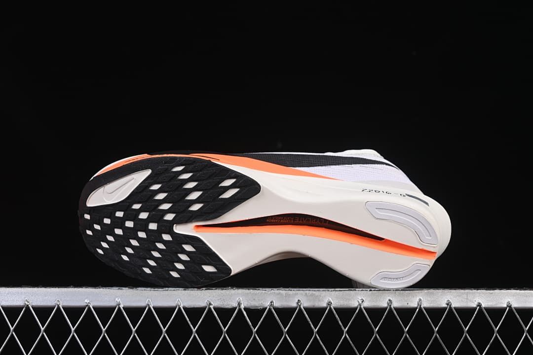 Underside view showing the black patterned outsole and orange midsole detail.
