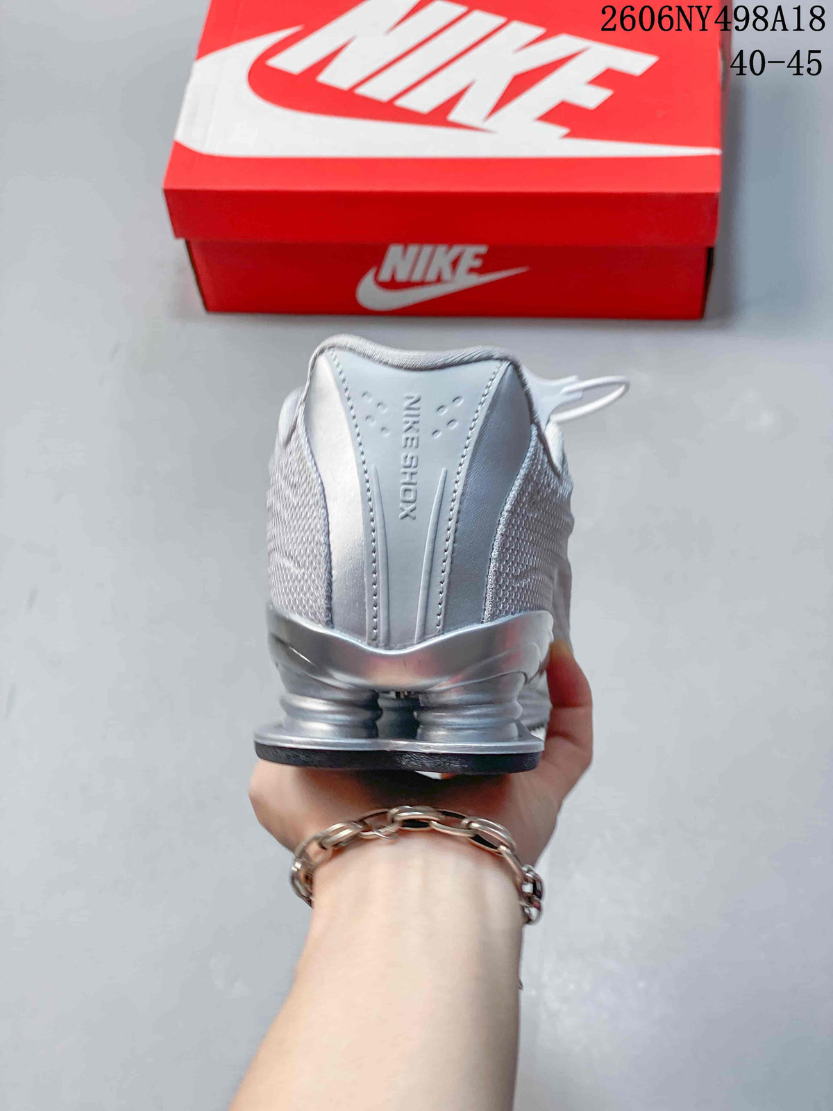 Rear view of a silver Nike Shox TL sneaker showing the heel columns