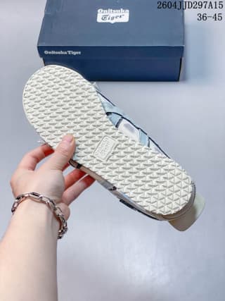 Underside view showing the sneaker's patterned rubber outsole and branded box.