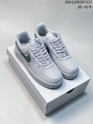 Pair of light Nike Air Force 1 '07 LV8 sneakers displayed on a shoebox, with dark green Swooshes visible.