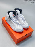 Pair of white and light gray Nike Inflict 4 wrestling shoes with black and orange accents, shown on an orange shoe box.
