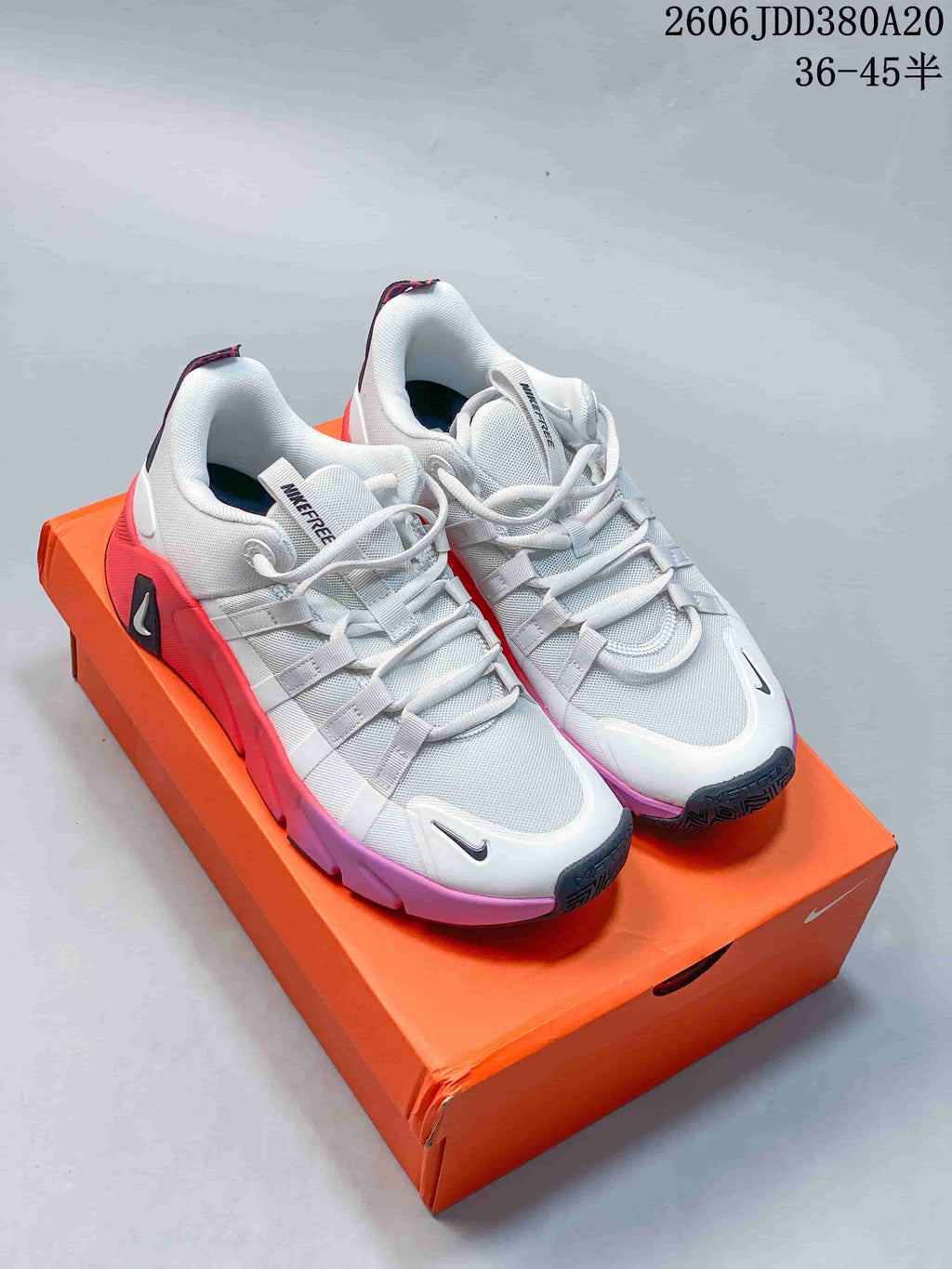 Pair of white Nike Free Metcon 7 training shoes with coral and purple accents, shown on an orange shoebox.