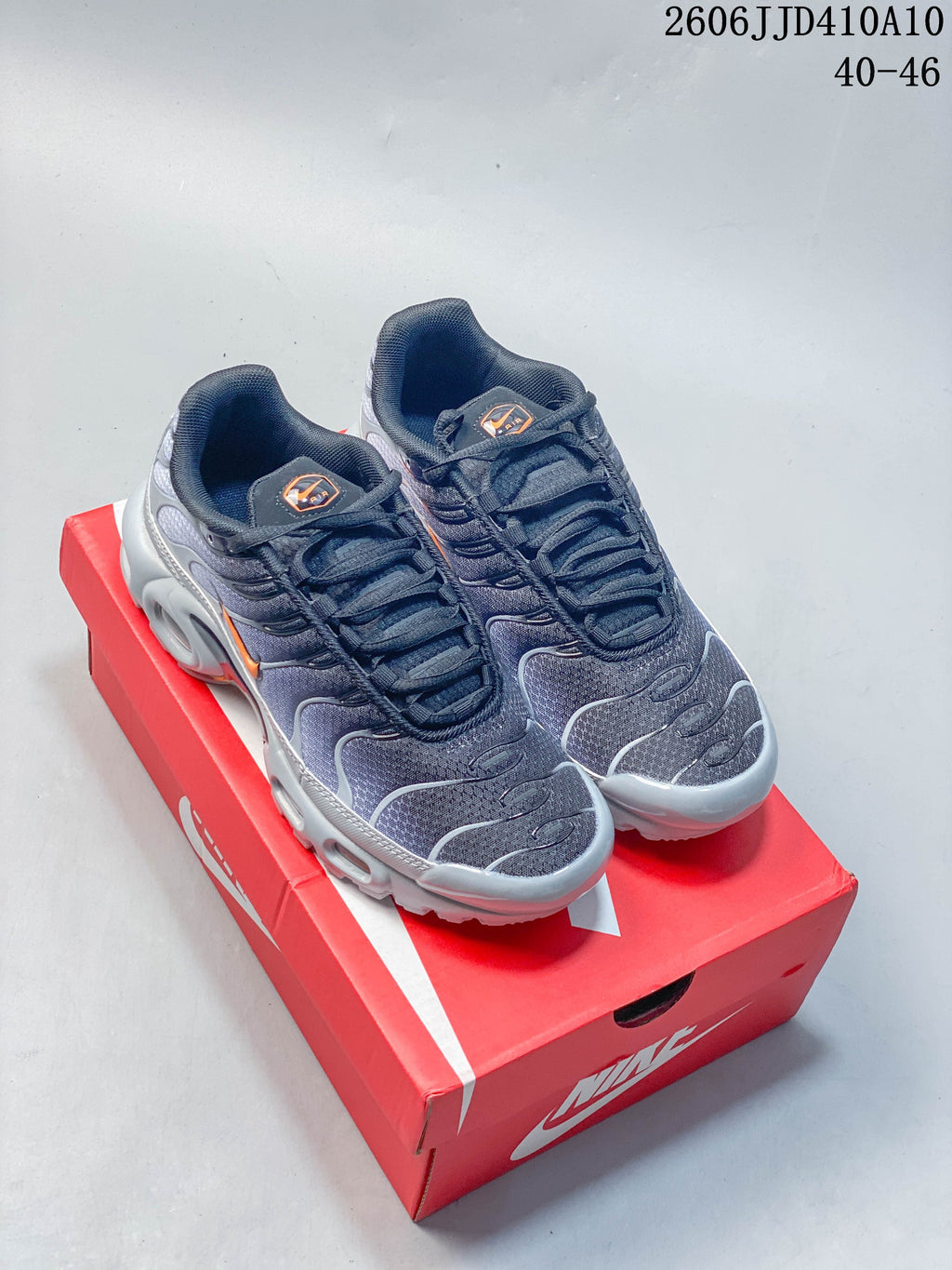 Dark gray Nike Air Max 95 sneakers with orange accents, displayed on a red shoe box.