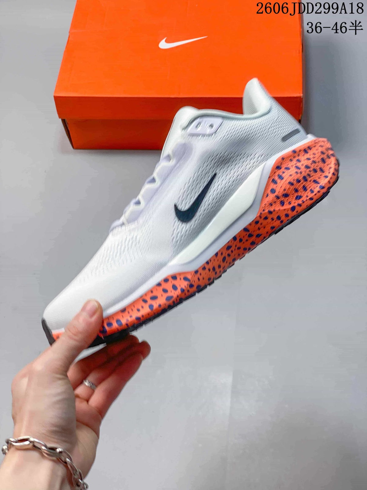 Side view of a white Nike running shoe with a dark Swoosh and orange speckled midsole.