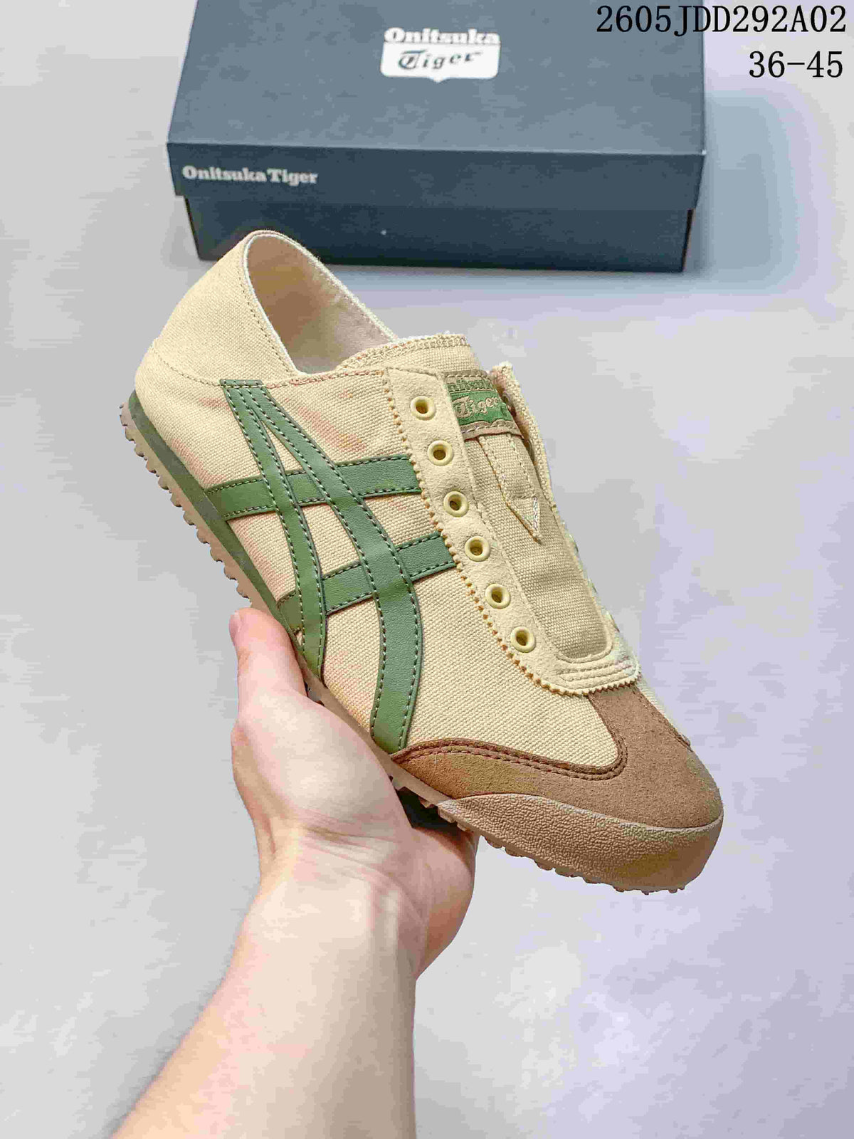Angled side view of the beige Onitsuka Tiger slip-on sneaker with green stripes and brown-toned toe overlay.