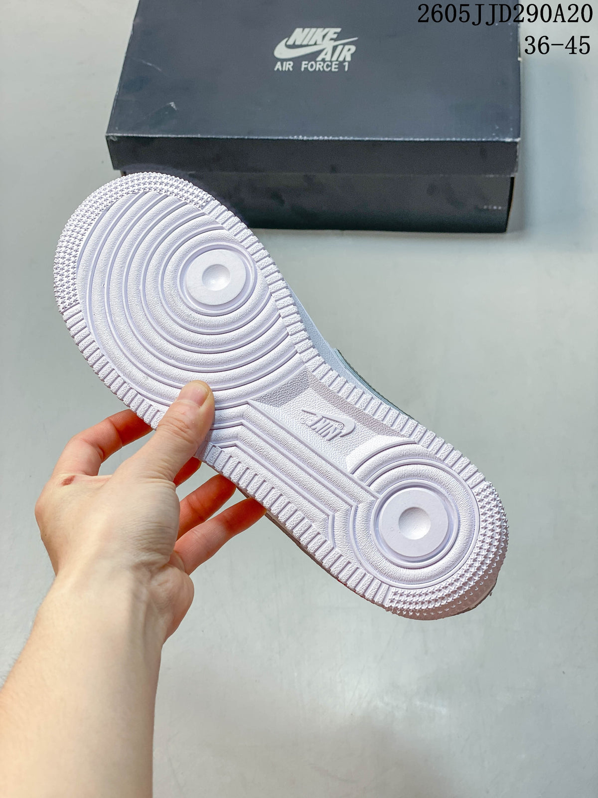 Underside view of a white sneaker showing the circular tread pattern and textured outsole.