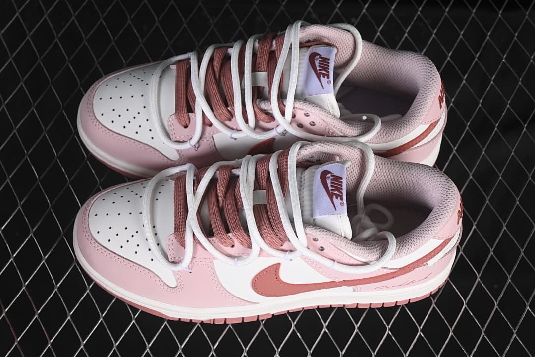 Top view of a pair of pink and white Nike SB Dunk Low sneakers with mixed-color laces and perforated toe boxes.