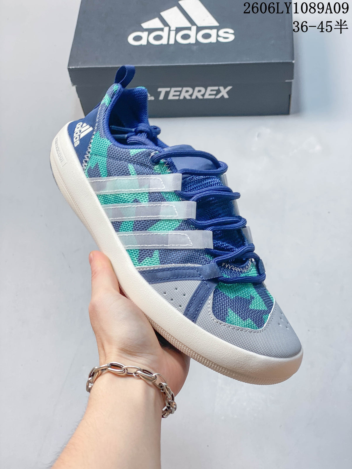 Close-up of a blue, gray, and teal graphic Adidas shoe with a lace-up front.
