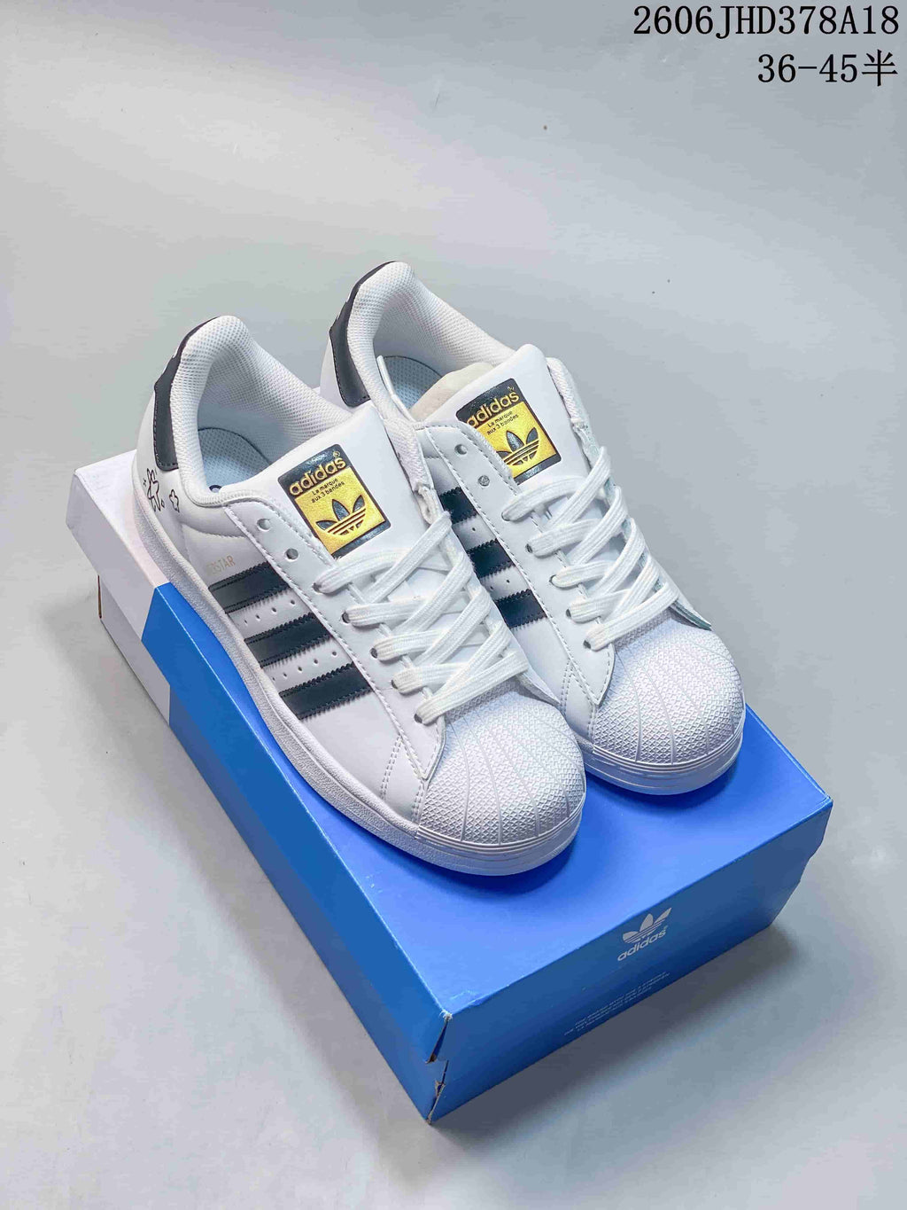 Pair of white Adidas Originals Superstar low-top sneakers with dark stripes and shell-style toes