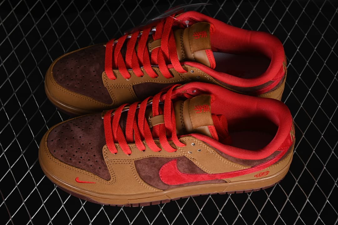 Pair of brown Nike SB Dunk Low sneakers with red laces, red Swooshes, and dark brown toe panels