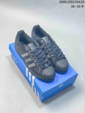 Dark gray Adidas Originals Superstar sneakers displayed on a blue shoebox