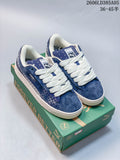 Pair of blue PUMA Suede XL sneakers with white laces and patterned side panels, shown on a green shoebox.