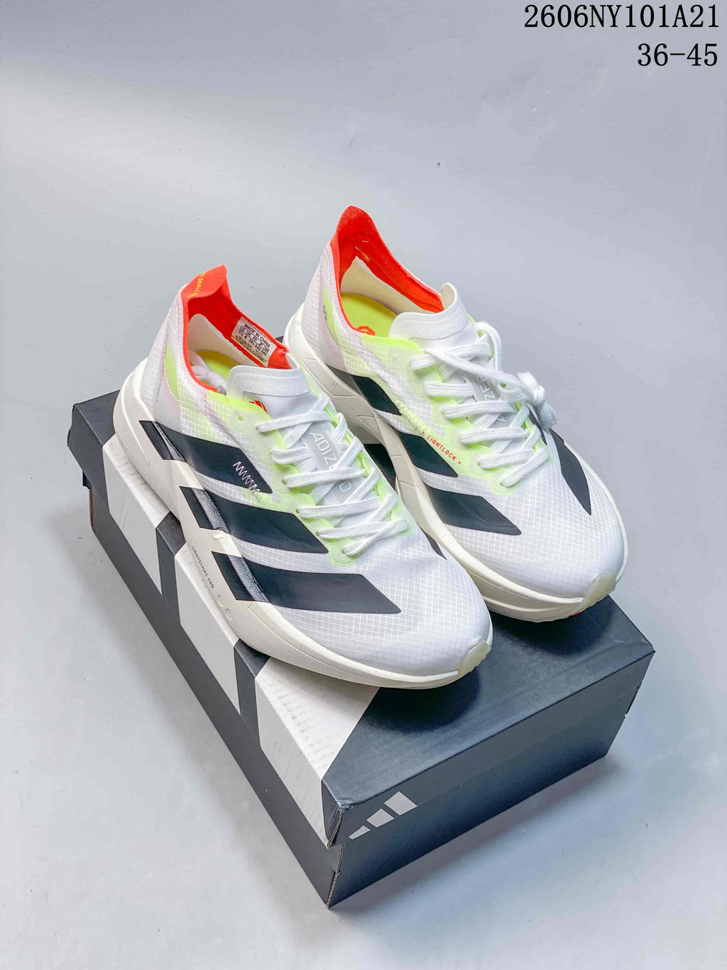 Pair of white Adidas running shoes with dark stripes, neon accents, and orange-red heel details.