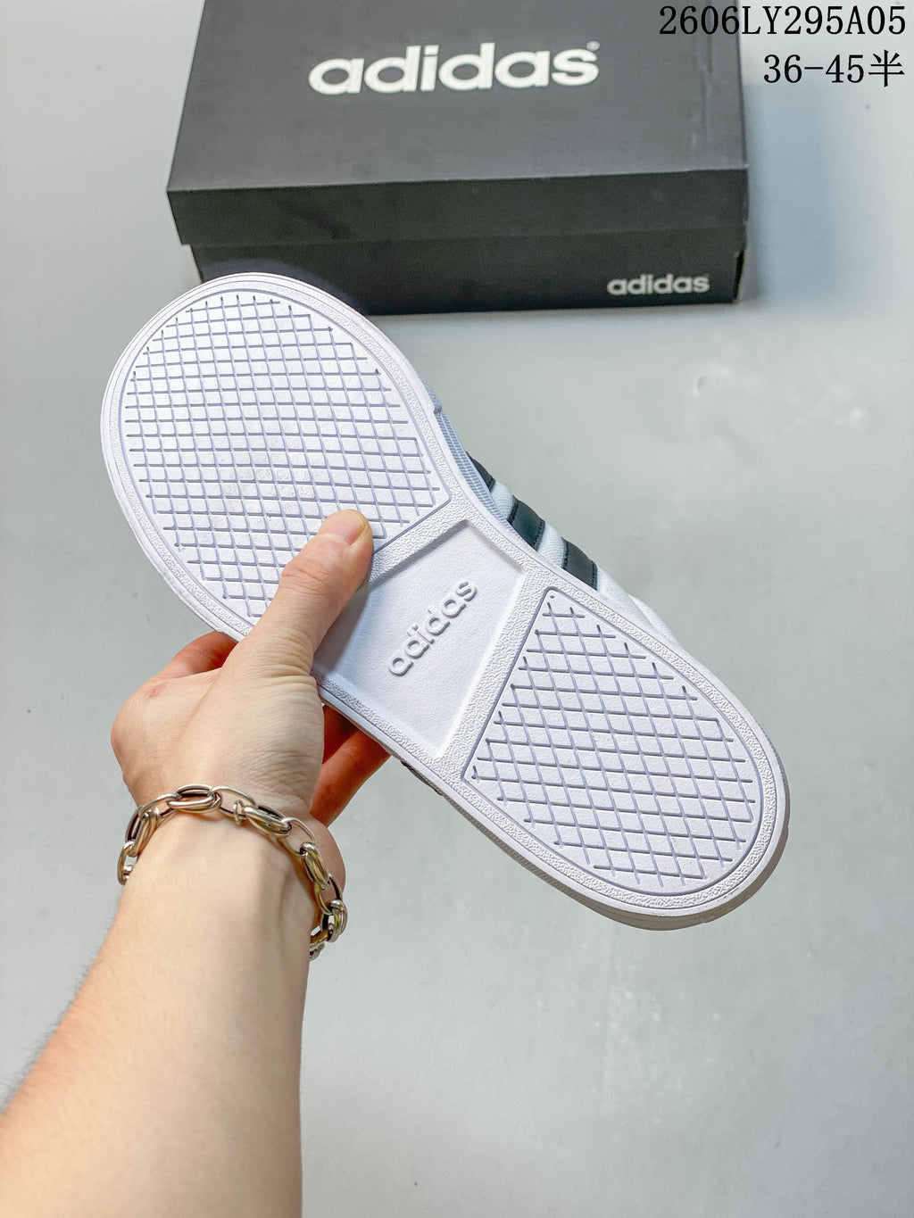 Underside of the white sneaker showing a patterned rubber outsole