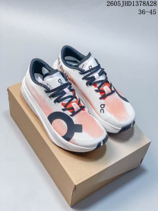 Pair of white and coral On Cloudboom Volt shoes displayed on a box.