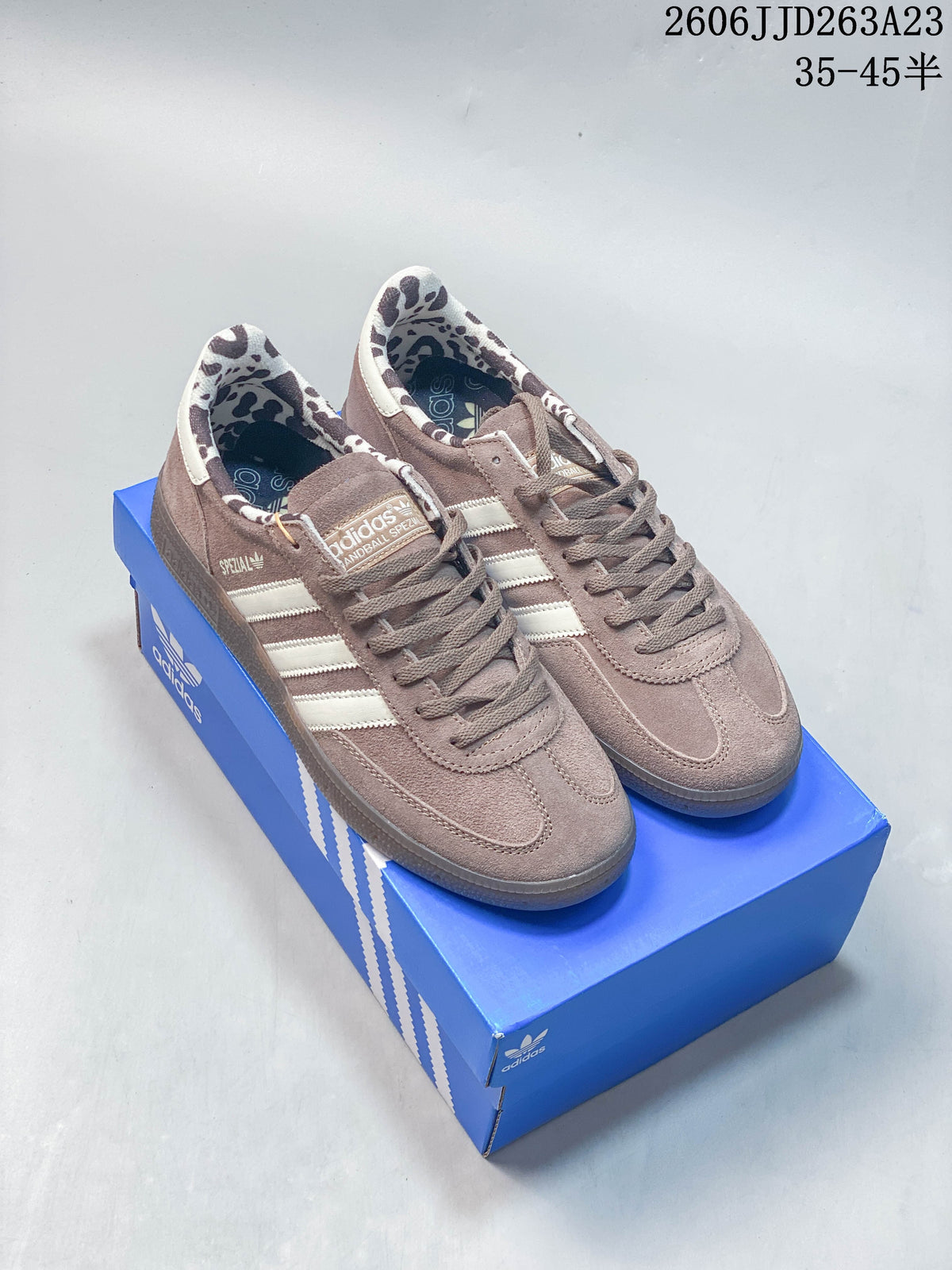 Pair of taupe and off-white Adidas Handball Spezial sneakers showing the patterned lining and gum-colored outsole.