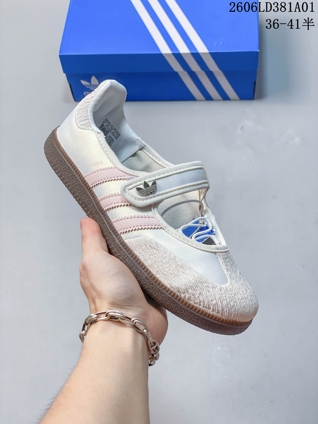 Angled side view of the white sneaker with pale pink stripes and gum-colored sole