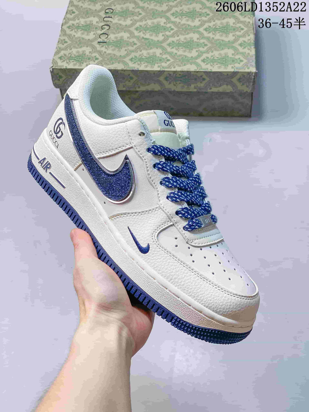 Angled view of a white and blue low-top sneaker with perforated toe and Gucci branding; image text shows style code 2606LD1352A22 and size range 36–45.5.