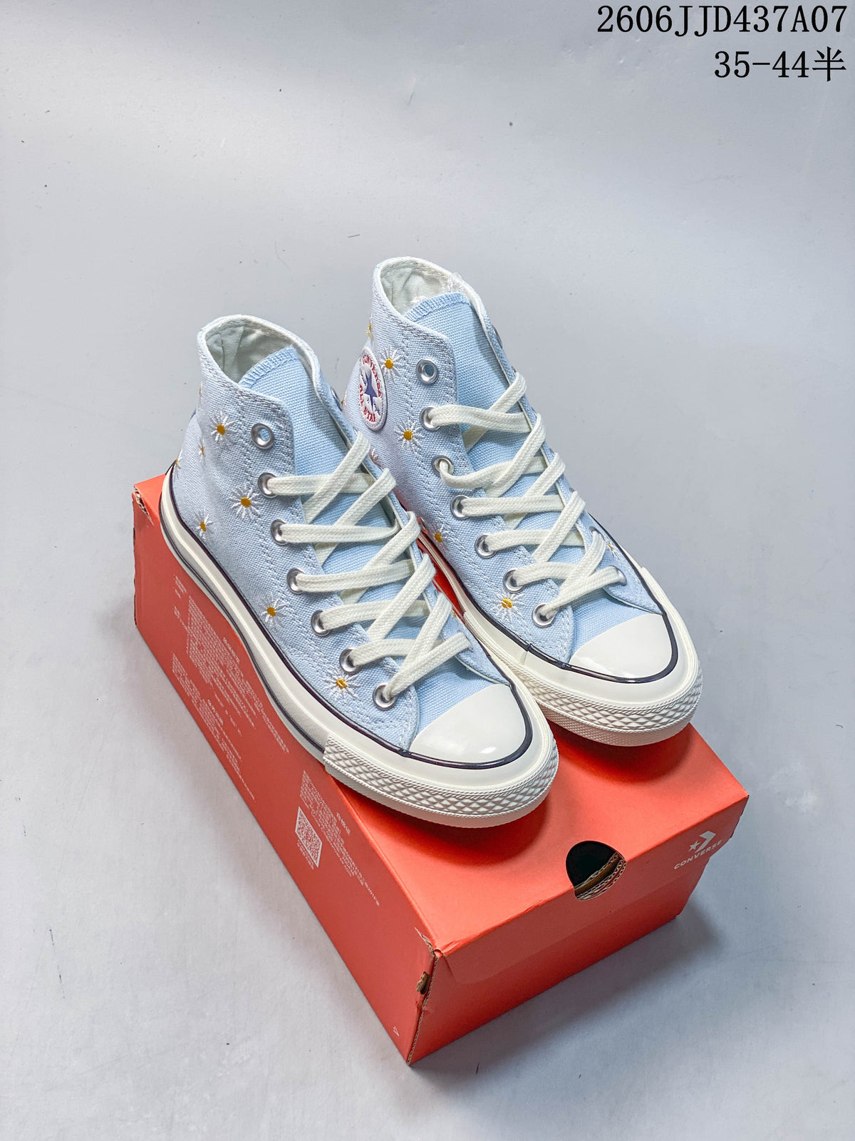 Pair of light blue high-top sneakers with embroidered daisies, cream laces and toe caps
