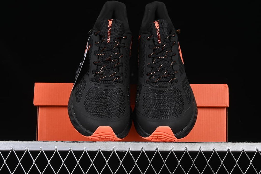 Front view of the pair of black shoes with coral-orange outsole accents.