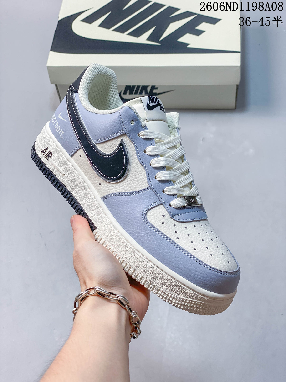 Angled view of one light-blue and off-white low-top sneaker with dark Swoosh panel, white laces, and white midsole; image overlay shows code 2606ND1198A08 and size range 36–45.5.