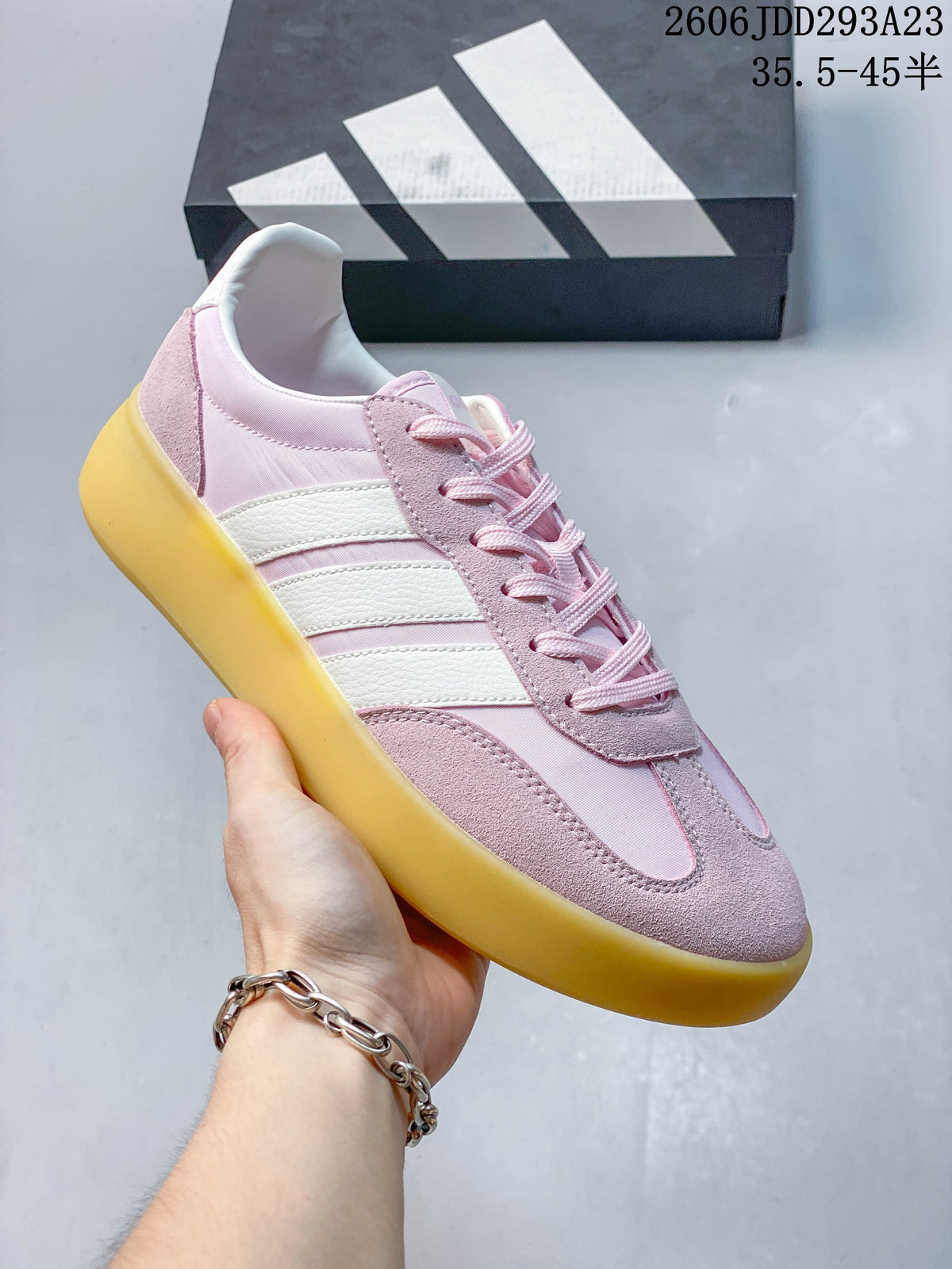 Close-up of a pink Adidas Barreda Decode sneaker with white side stripes and a contrasting yellow-toned sole.